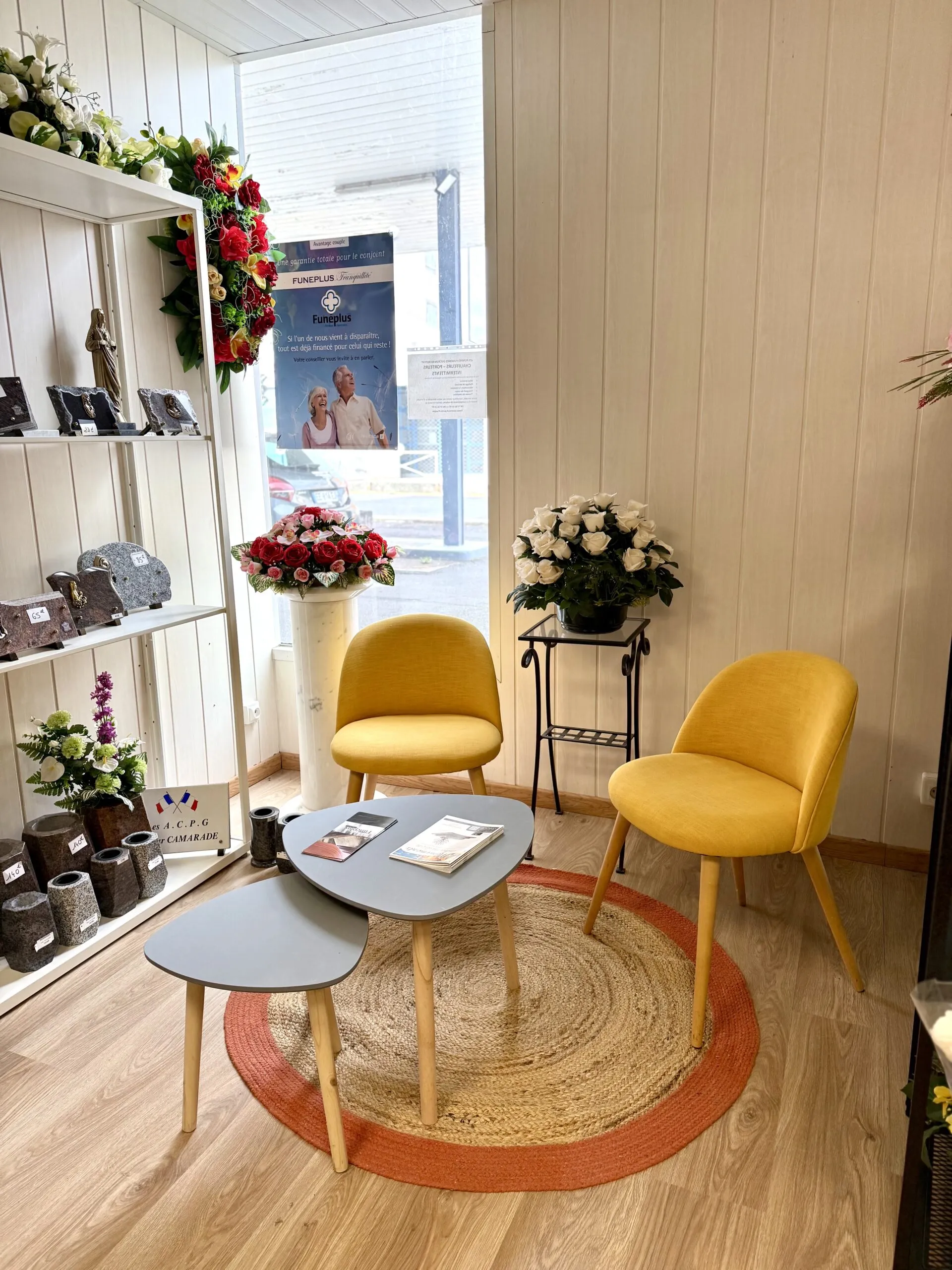 Espace de rendez-vous chaleureux avec fauteuils, fleurs et plaques funéraires en exposition