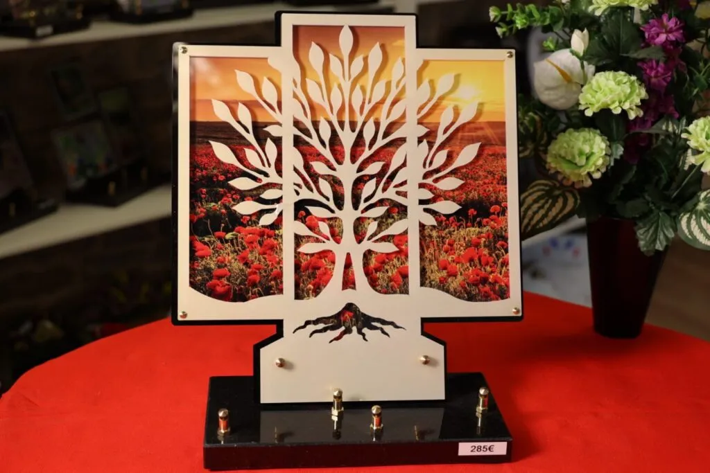 Plaque funéraire moderne découpée représentant un arbre de vie sur fond de champ de coquelicots
